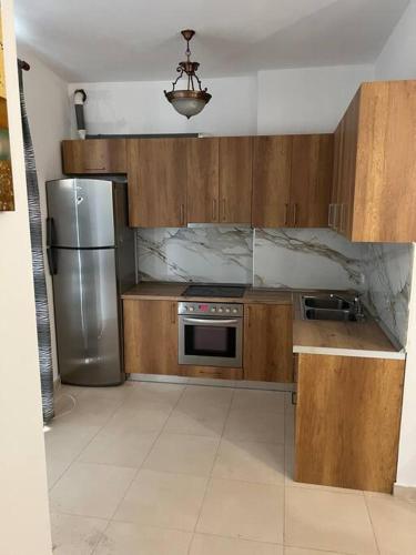 地拉那Apartment Astiri的厨房配有木制橱柜和不锈钢冰箱。