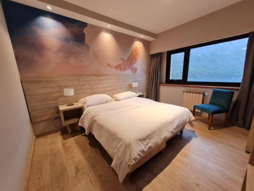 圣卡洛斯-德巴里洛切Hotel Alun Nehuen的一间卧室配有一张大床和一张蓝色椅子
