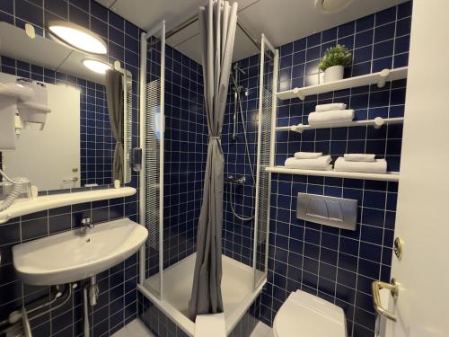 海德利桑德Adventure Hotel Hellissandur的蓝色瓷砖浴室配有淋浴和盥洗盆