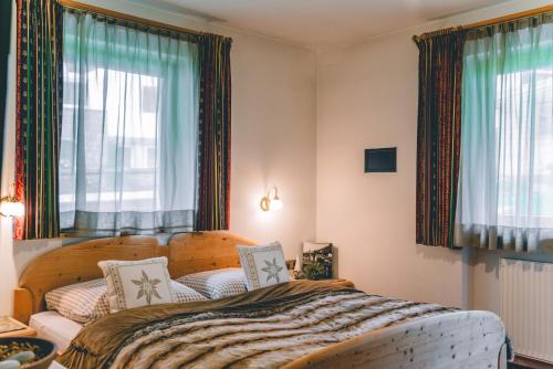 圣克里斯蒂娜Garni Hotel Belalp的一间卧室设有一张床和两个窗户。
