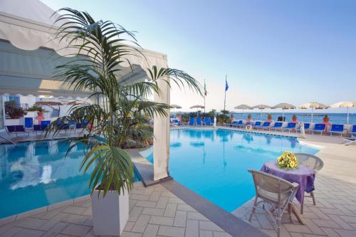 伊斯基亚Hotel Solemare Beach & Beauty SPA的一个带桌子和棕榈树的大型游泳池