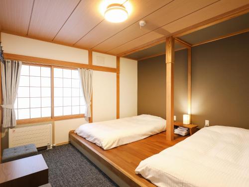 美瑛町RONENAI BASE的一间卧室设有两张床和窗户。