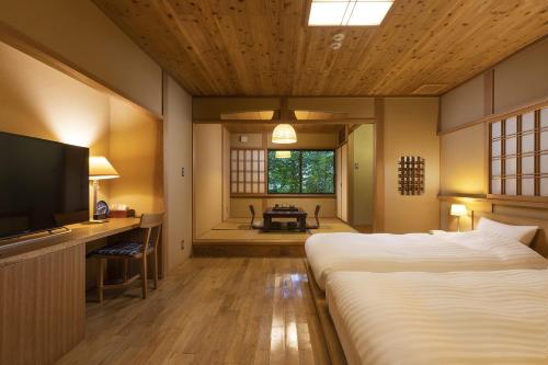 由布市汤布院茶寮日式旅馆的一间卧室配有一张大床和电视
