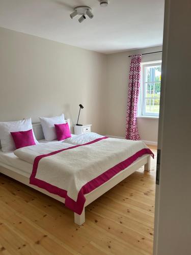 BlumenowStorchenhof Blumenow的白色卧室配有带粉红色枕头的大床