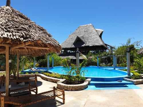 米查维Jua Peponi的一个带游泳池和茅草屋顶的度假胜地