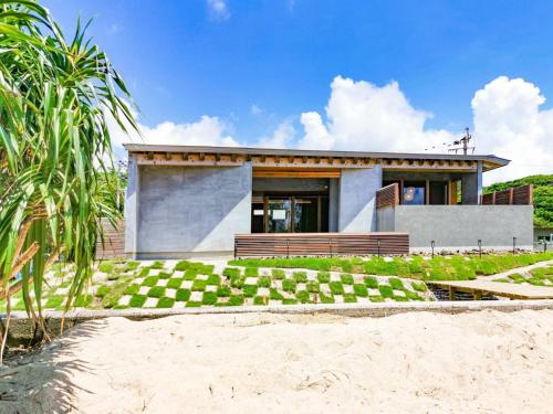 奄美Amami 与庵的海滩上一棵棕榈树的房子