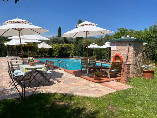 LarcianoAgriturismo Podere Marchiano的一个带遮阳伞和壁炉的庭院,毗邻一个游泳池