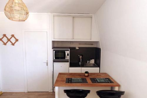 桑利斯Le petit studio senlisien的厨房配有白色橱柜和木制台面
