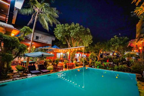 峰牙Phong Nha Tuan Garden House的夜间游泳池,配有桌椅