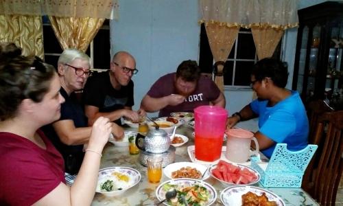 甲抛峇底Homestay Teratak Kayu kota Aur的一群坐在桌子旁吃食物的人