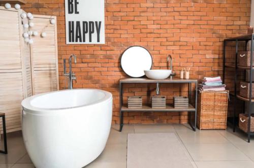 Bến CátHappy 1 Hotel Binh Duong的一间带白色浴缸和砖墙的浴室