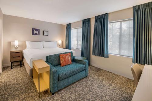 安多弗Sonesta ES Suites Andover Boston的配有一张床和一把椅子的酒店客房