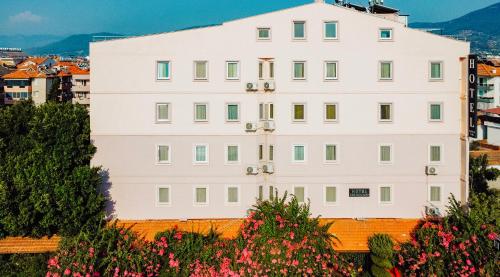 达拉曼Karacan Park Hotel -Dalaman Airport的山上的白色建筑,花朵繁多