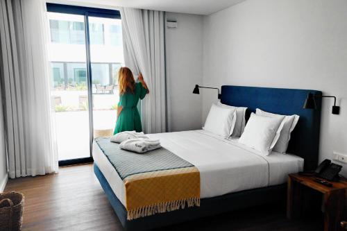 蓬塔德尔加达Pêro Teive Bay Apartments Hotel的一位妇女站在酒店带床的房间