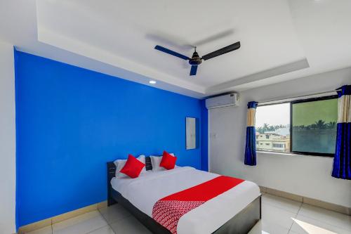 KhandagiriSPOT ON Hotel Utrishree的蓝色卧室,配有红色枕头的床