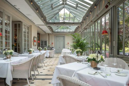 巴登-巴登布莱内公园Spa酒店 - 欧特家系列酒店的餐厅设有白色的桌椅和玻璃天花板