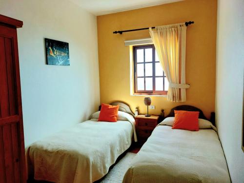 巴尔洛文托Las Paredes的一间卧室配有两张带橙色枕头的床