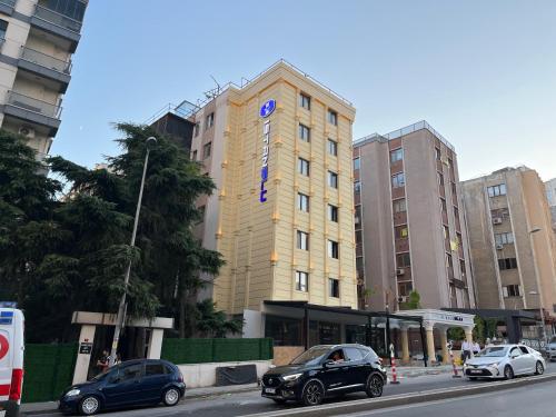 伊斯坦布尔Istanblu Hotel Ataşehir的一座高大的建筑,前面有汽车停放