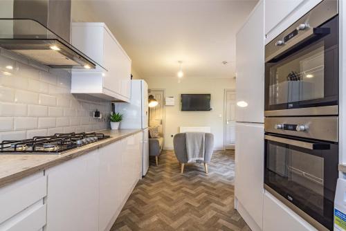 德比Stay @ Baker Street Derby的厨房配有白色橱柜和炉灶烤箱。