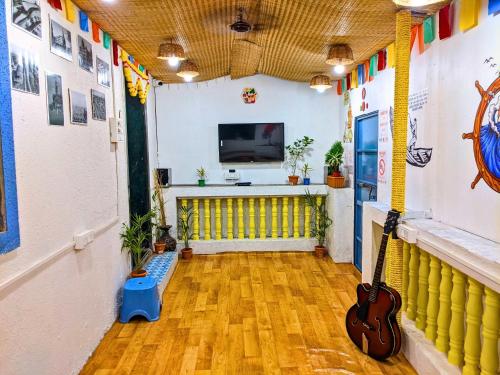 阿里巴格Awaara Backpackers Hostel, Alibag的一间设有吉他和电视的房间