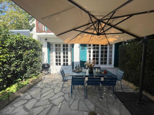 多维尔Villa normande - Les Crapauds Fous的露台配有桌椅和遮阳伞