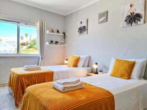 卡武埃鲁CASA TÔMBUA - Pool - Beach & Center 300m - AC - WiFi的一间卧室设有两张带橙色床单的床和窗户。