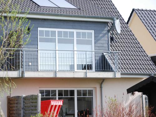 奥斯特巴特宁哈根Exkl App Kliff am Meer, W-LAN, Balkon的带阳台和红色椅子的房子