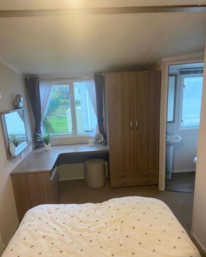 彭布罗克郡Tenby - Kiln Park caravan hire的卧室配有一张床、一张书桌和窗户。