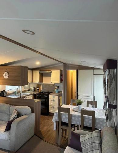 彭布罗克郡Tenby - Kiln Park caravan hire的厨房以及带桌椅的起居室。