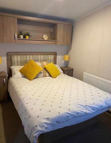 彭布罗克郡Tenby - Kiln Park caravan hire的一间卧室配有一张带黄色枕头的大床