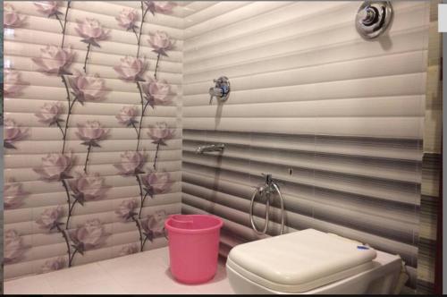 莫尔穆冈HOTEL AVISHA Residency的浴室设有粉红色的卫生间,墙上挂有鲜花
