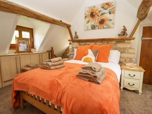 切尔滕纳姆Manor Farm的一间卧室配有一张带橙色毯子的大床