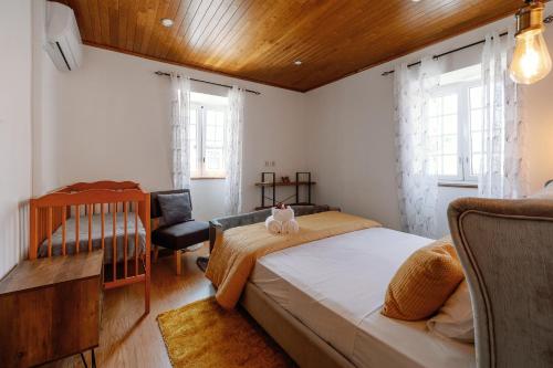 布拉干萨Casa do Javali的一间卧室配有一张床和一把椅子,还有两个窗户
