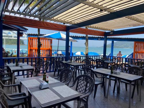 乌巴图巴Kaliman Luxo Pousada的一间空餐厅,配有桌椅,享有海景