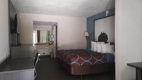 达尼亚滩Super 8 Motel by Wyndham near Fort Lauderdale Arpt的酒店客房设有一张床和一面大镜子