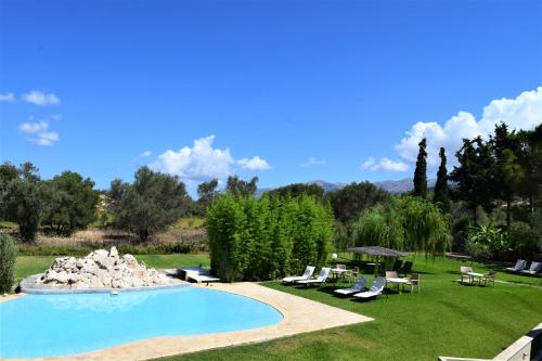 拉瑟Simatos αpARTments & Studios的庭院内的游泳池,带椅子和树木
