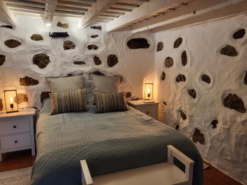 克鲁兹·德·特赫达Casa Rural LOS PINARES El Juncal de TEJEDA的一间卧室设有石墙和床
