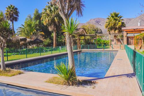 El MolleHotel Naturaleza Vertientes de Elqui的一座棕榈树和围栏的游泳池