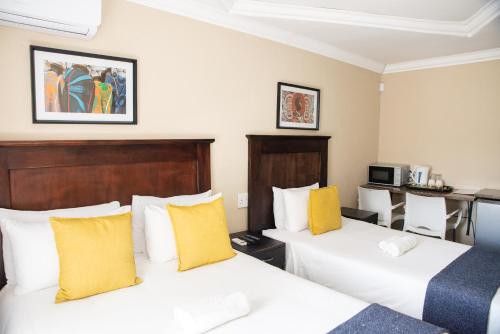 波罗瓜尼M n M Guesthouse In Turfloop Mankweng的配有黄色枕头的酒店客房的两张床
