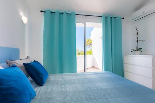 锡蒂奥卡拉翁达Villa Las Margaritas的一间卧室配有蓝色窗帘和一张带窗户的床