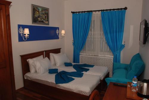 埃尔代克蓝色珍珠公园酒店的一间卧室配有一张带蓝色窗帘的床和一把椅子