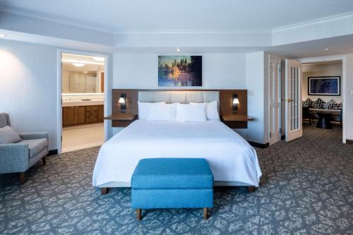 波特兰Embassy Suites by Hilton Portland Airport的卧室配有一张白色大床和蓝色凳子