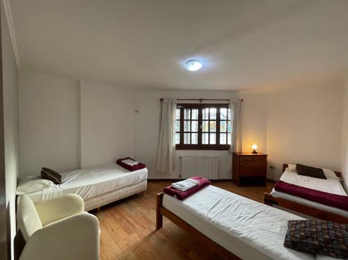 埃斯克尔Hotel Pintó Terraza的客房设有两张床、一把椅子和窗户。