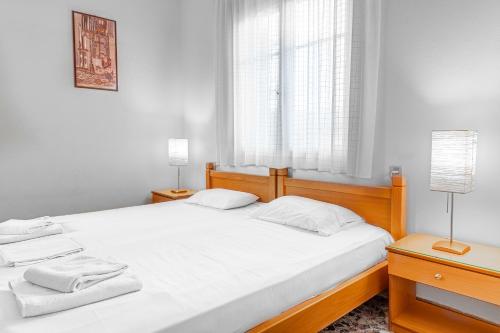 斯卡拉埃雷索La Skala Eressos Holiday Apartments的一间卧室配有一张带白色床单的床和一扇窗户。