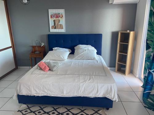 普纳奥亚Punaauia Panoramic View的一张蓝色的床,上面有白色的床单和枕头