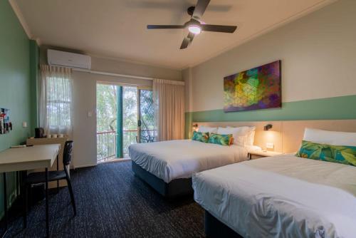 玛志洛Nightcap at Waterfront Hotel的酒店客房设有两张床、一张书桌和一个窗户。
