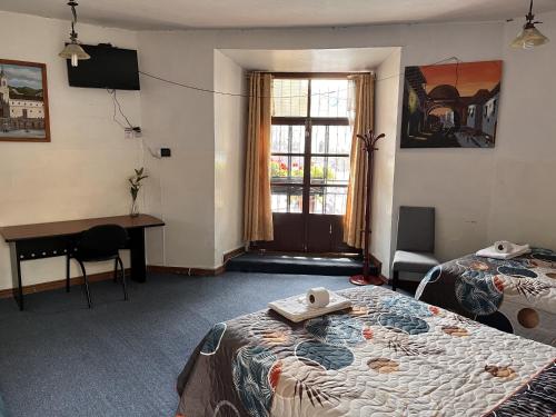 基多Hostal Benalcazar的客房设有两张床、一张桌子和一个窗户。