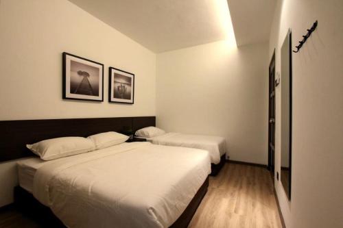 马六甲新概念-新设计KonZept 1 house near Jonker&Heritage的卧室配有两张床,墙上挂有两张照片