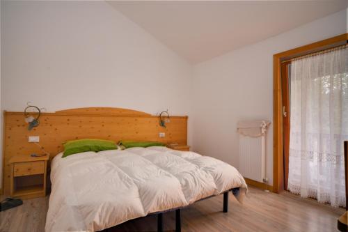 SirorLocanda Val Canali的一间卧室配有一张带木制床头板的床和窗户。