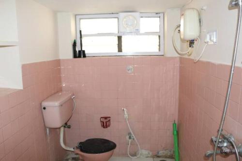 海得拉巴The Ghosh's Home stay的粉红色的瓷砖浴室设有卫生间和窗户